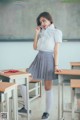 A woman in a school uniform standing in front of a blackboard.