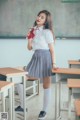 A woman in a school uniform standing in front of a blackboard.