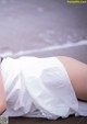 A woman in a white dress laying on the beach.