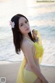 A woman in a yellow bikini standing on a beach.