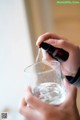 A person pouring water into a glass of water.