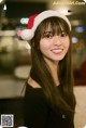 A woman wearing a santa hat smiles at the camera.