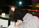 A woman in a black and white checkered skirt bending over a table.