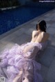 A woman in a purple dress sitting by a swimming pool.