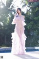 A woman in a pink dress standing next to a pool.