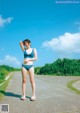 A woman in a blue bikini standing on a road.