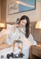 A woman sitting on a bed talking on a phone.