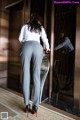 A woman in a white shirt and gray pants standing in an elevator.