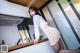 A woman in a white shirt and skirt leaning over a kitchen counter.