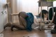 A woman in a school uniform laying on the floor next to a desk.