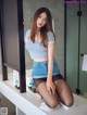 A woman sitting on a counter in a bathroom.