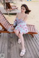 A woman sitting on a wooden bench on the beach.