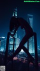 A woman standing on top of a metal railing in front of a city.