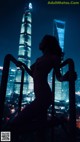 A woman standing on top of a metal railing in front of a city.