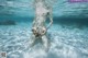 A woman holding a starfish underwater in the ocean.