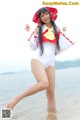 A woman in a white bathing suit and red hat on the beach.