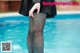 A woman in black tights standing next to a swimming pool.