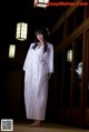 A woman in a white kimono standing in a room.