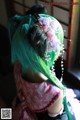 A doll with green hair and a flower in her hair.