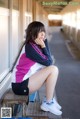 A woman sitting on a bench with her legs crossed.