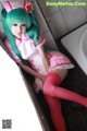 A woman in a pink and green nurse outfit sitting in a bathtub.