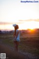 A woman in a sailor outfit standing in a field at sunset.