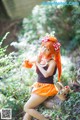 A woman with long orange hair sitting on a log in the woods.