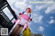 A woman in a pink and white outfit holding a yellow bag.