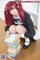 A woman in a maid outfit sitting on a pile of books.