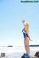 A woman in a bathing suit standing on a rock by the ocean.