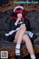 A woman in a maid outfit sitting on a couch.