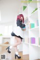 A woman in a maid outfit is standing in front of a bookshelf.