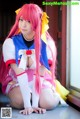 A woman with long pink hair sitting on the floor.