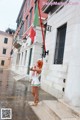 A woman in a white dress holding a red and green flag.