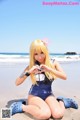 A woman sitting on the beach making a heart with her hands.