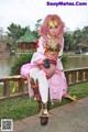 A woman in a pink and gold outfit sitting on a bench.