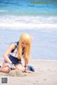 A woman in a sailor outfit sitting on the beach.