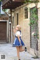 A woman in a blue and white dress is walking down a street.