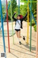 A young woman in a school uniform is playing on a playground.