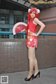 A woman in a red dress holding a red fan.