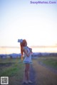 A woman in a sailor outfit standing on a dirt road.