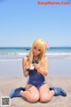 A woman in a blue bathing suit sitting on the beach.