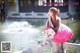 A woman in a pink dress sitting on a bridge.