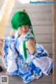 A woman with green hair sitting on a wooden floor.