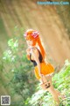 A woman in an orange dress holding a basket in the woods.