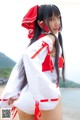 A woman in a white and red outfit standing on a beach.