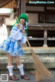 A woman in a blue and white dress holding a broom.