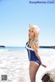 A woman in a blue and white bathing suit standing on a beach.