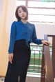 A woman in a blue shirt and black skirt posing for a picture.