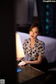 A woman sitting at a desk in front of a lamp.